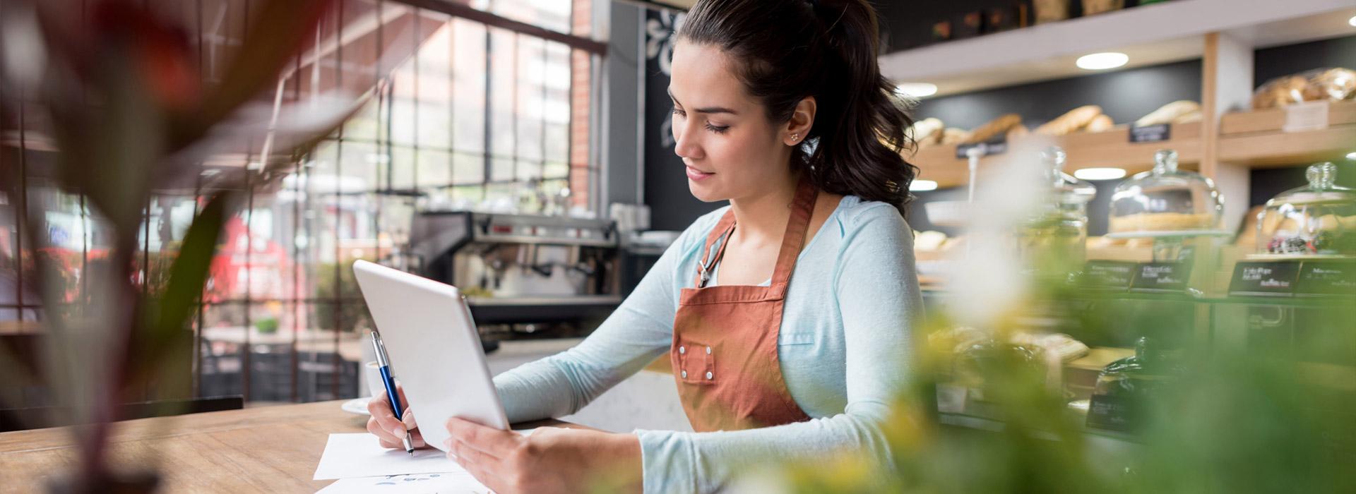 coffee shop manager doing paperwork and holding computer tablet