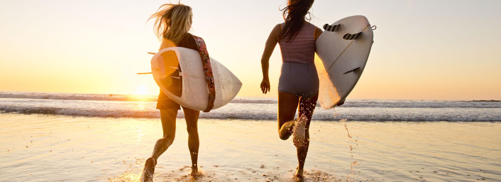 Women surfers walking on beach