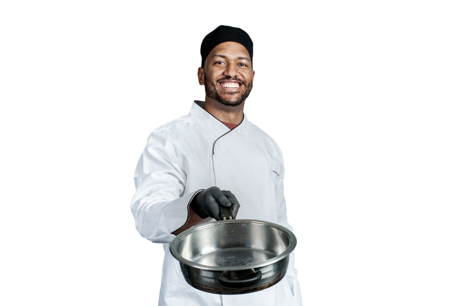 Smiling chef in white uniform and black cap holding empty stainless steel pan against white background.